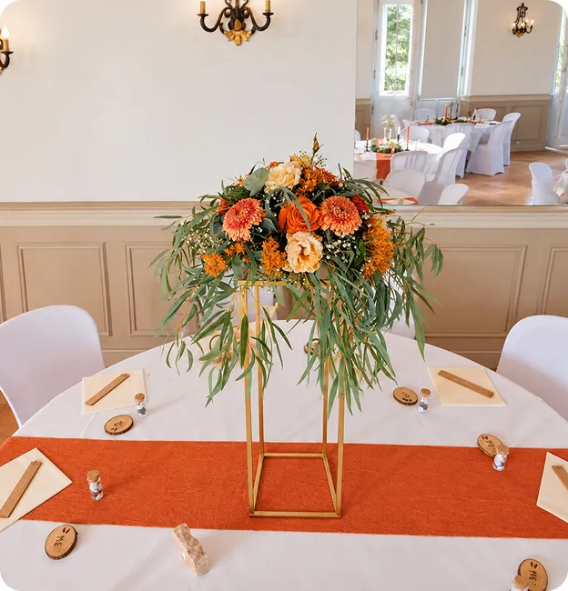 Centre de table floral aux tons automnaux sur une nappe orange