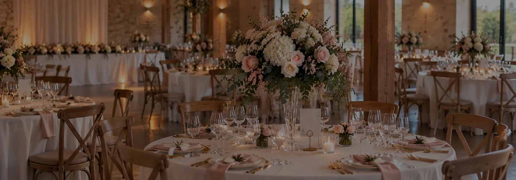 Salle de réception de mariage aux tables rondes fleuries de roses et d’hortensias
