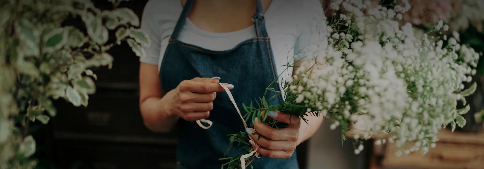 Fleuriste en tablier composant un bouquet de gypsophile et de feuillages